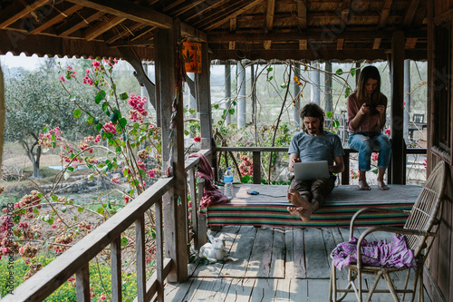 Traveling freelance couple sitting on balcony  with laptop computer  doing work and using internet