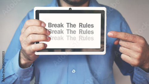 Businessman pointing Break The Rules word on a tablet screen.