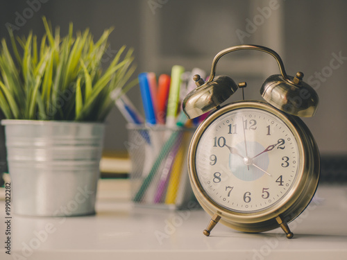 Vintage alarm clock and pen box, flower pot on table desk.