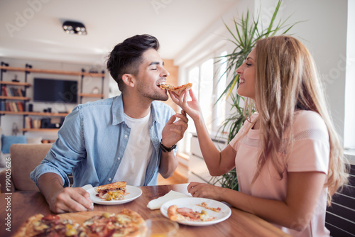 Young couple enjoying eating pizza at home