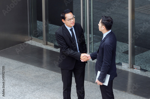 two business young asian smart man talking information about finance news together standing in front of Bank in city, congratulation, success, meeting, partner, teamwork, community, connection concept