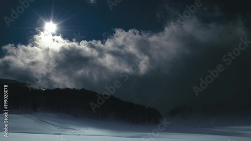 Moon shine, slow clouds and snow covered field. Winter night landscape