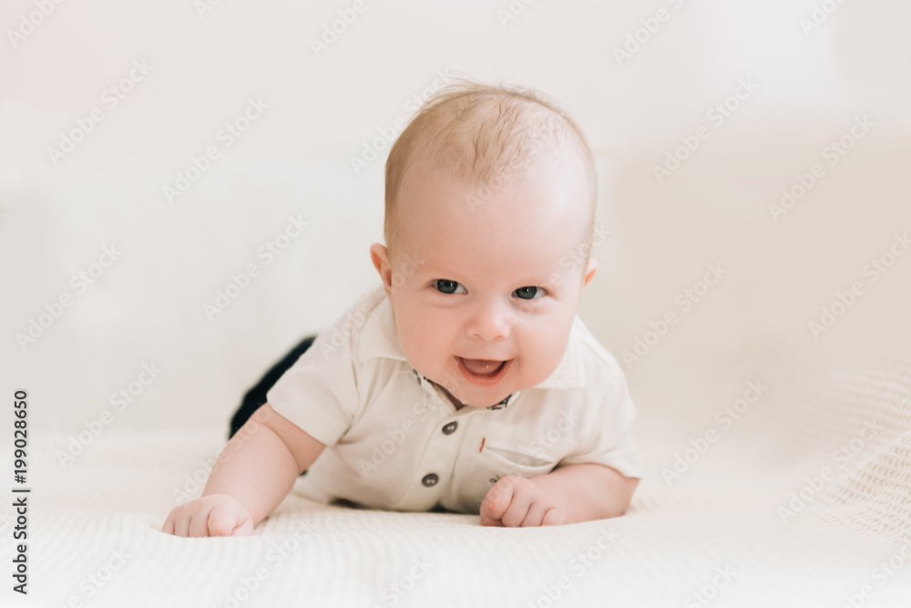 Handsome fashionable little boy lying on a blanket, with a sweet expression Handsome fashionable little boy lying on a blanket, with a sweet expression
