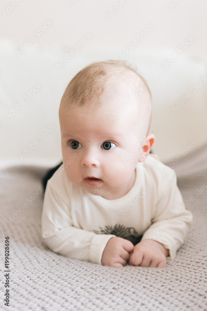 Handsome fashionable little boy lying on a blanket, with a sweet expression Handsome fashionable little boy lying on a blanket, with a sweet expression