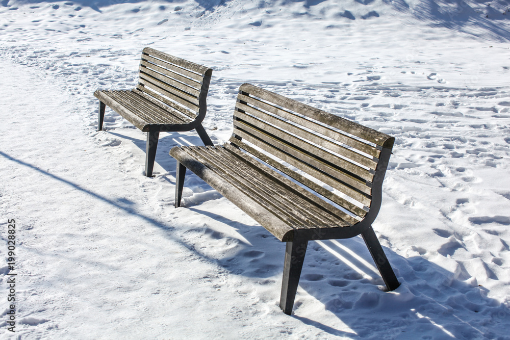 Two empty benches on snow covered ground