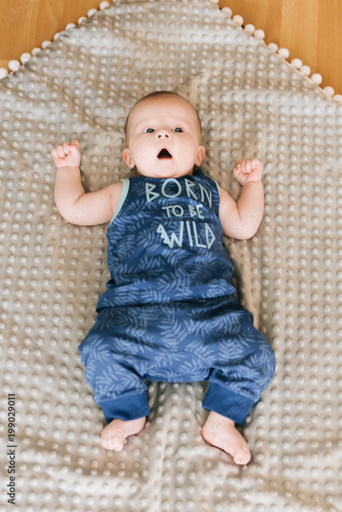 Handsome fashionable little boy lying on a blanket, with a sweet expression Handsome fashionable little boy lying on a blanket, with a sweet expression