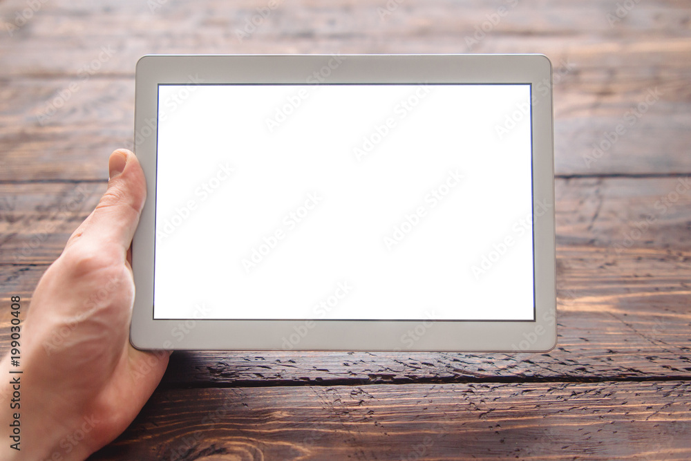 men's hand holding tablet with blank screen for your logo or design on dark wooden table men's hand holding tablet with blank screen for your logo or design on dark wooden table