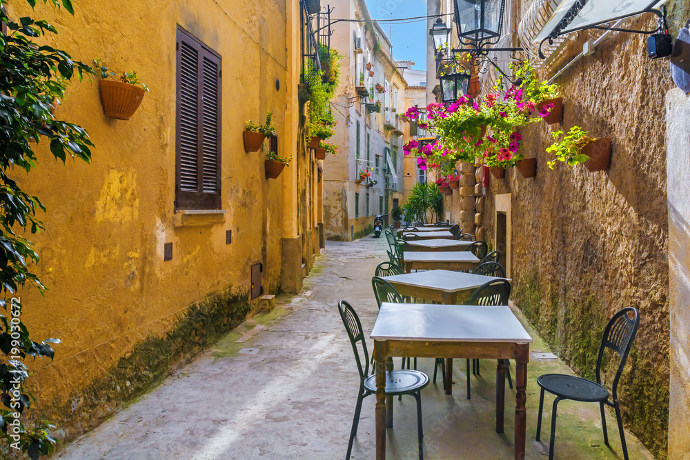 Cafe tables and chairs outside in old cozy street in the Positano town, Italy