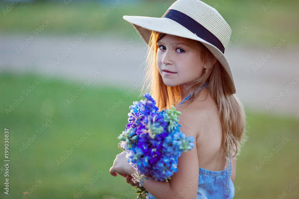 Girl in hat and with flowers at sunset