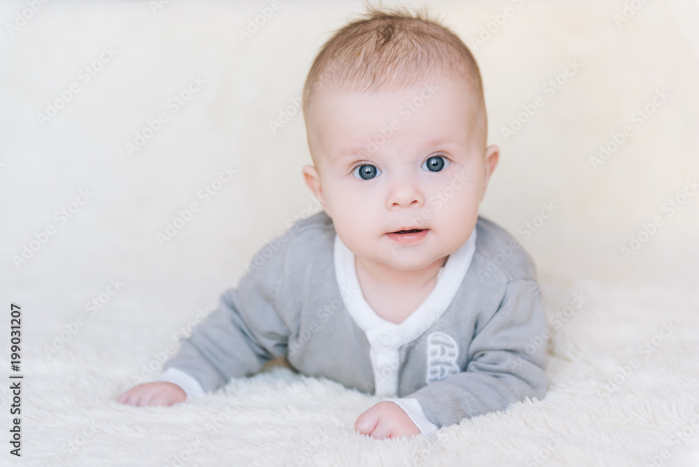 Small baby boy lying on stomach and raising his head awhile looking surprised and smiling cute, newborn Small baby boy lying on stomach and raising his head awhile looking surprised and smiling cute, newborn