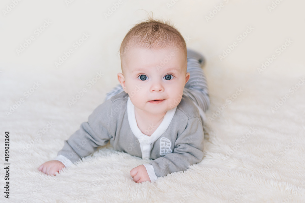 Small baby boy lying on stomach and raising his head awhile looking surprised and smiling cute, newborn Small baby boy lying on stomach and raising his head awhile looking surprised and smiling cute, newborn