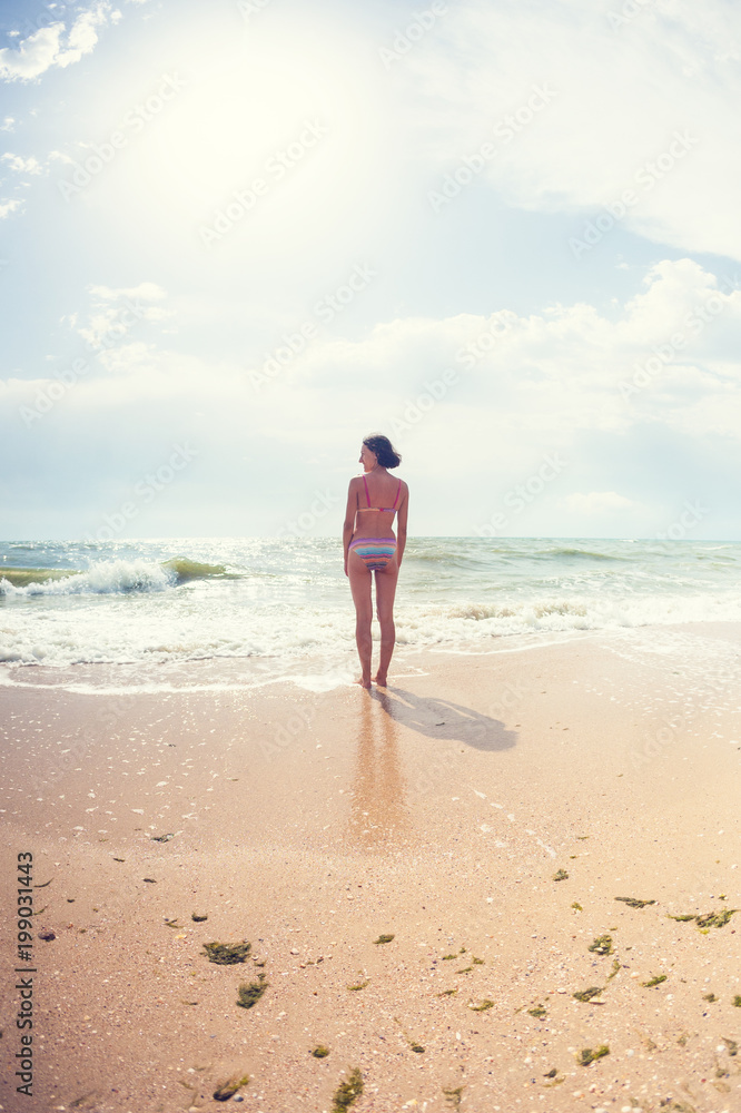 A girl is walking along the beach.