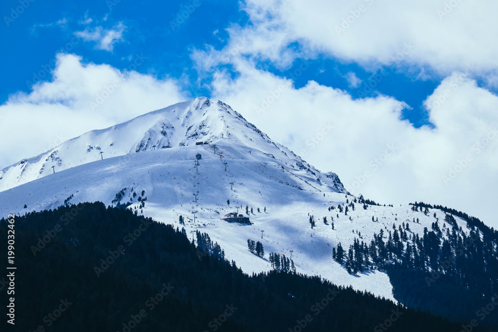 Mountain snow peak, beautiful natural winter backdrop. Ice top of the hill, blue sky background. Alpine landscape.