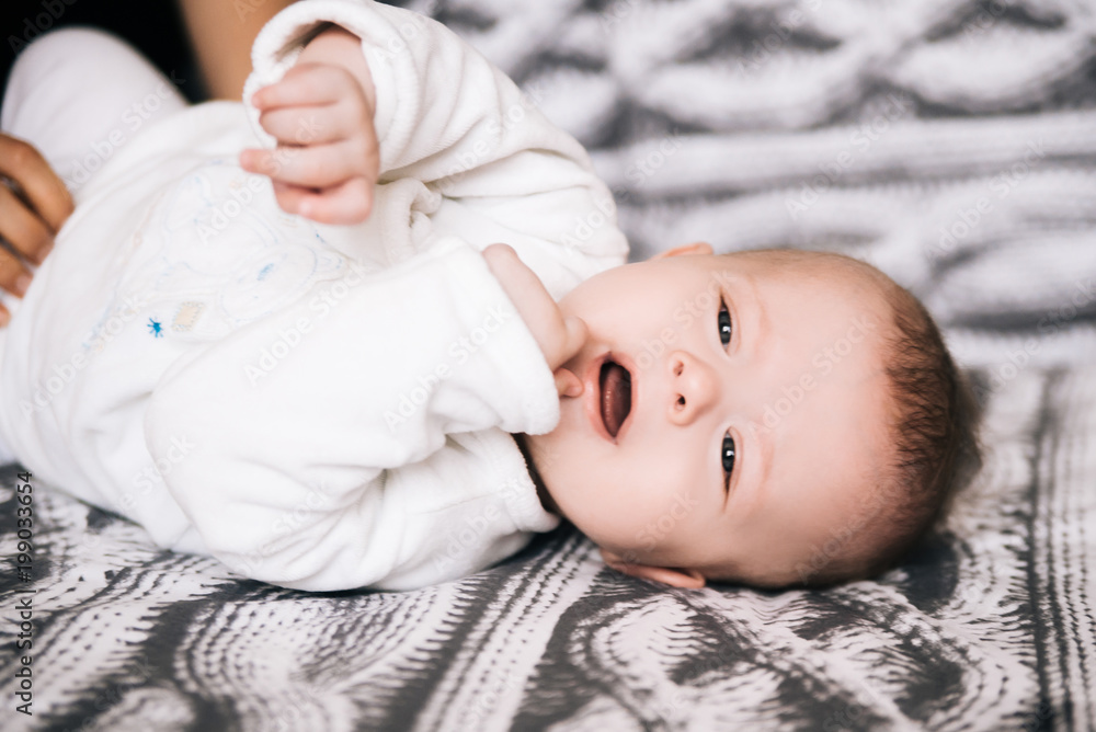 Cute newborn baby lying on back on white gray background, selective focus