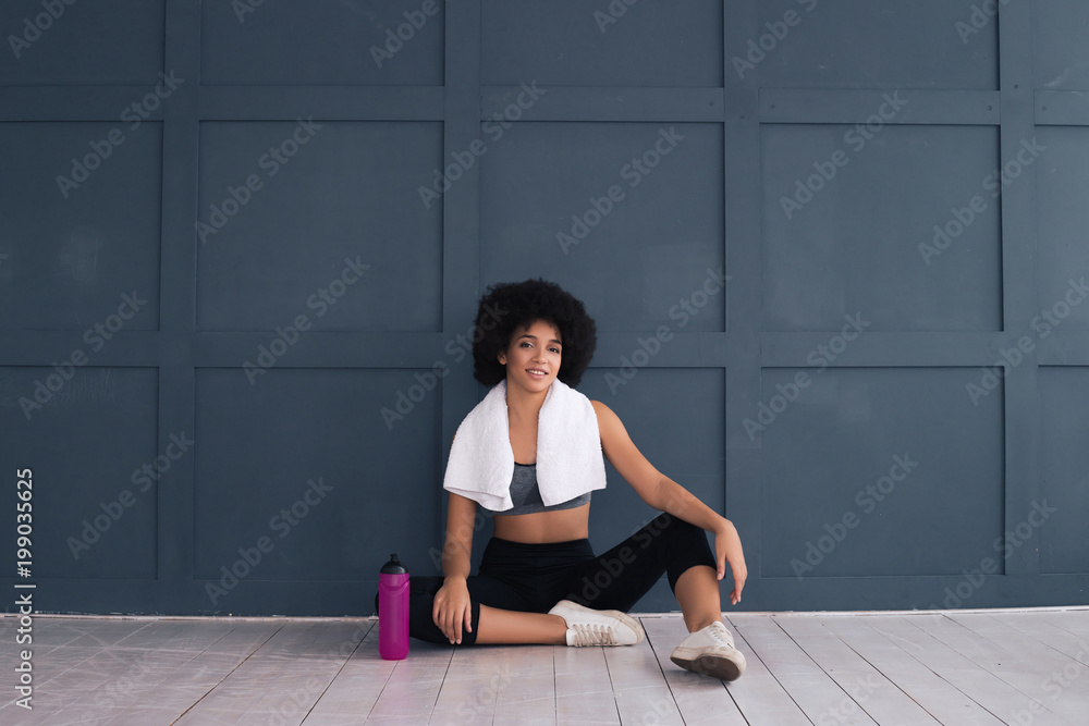 Fototapeta premium You have to start to be great! Good-looking beautiful young lady sitting on the floor after having done the sport with a white towel on her neck.