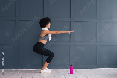 Commit to be fit! Good-looking gorgeous young lady doing sport with a white towel on her neck and modern water bottle in front.