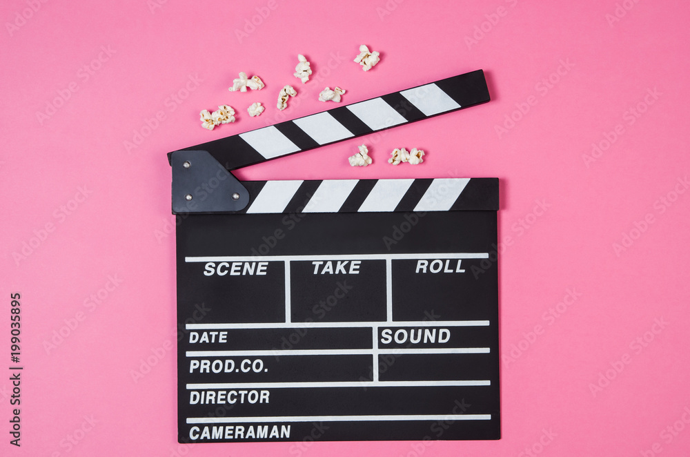 Fresh popcorn and movie clip isolated on pink background top view with copy space around products. Cinematic concept for blogs or design