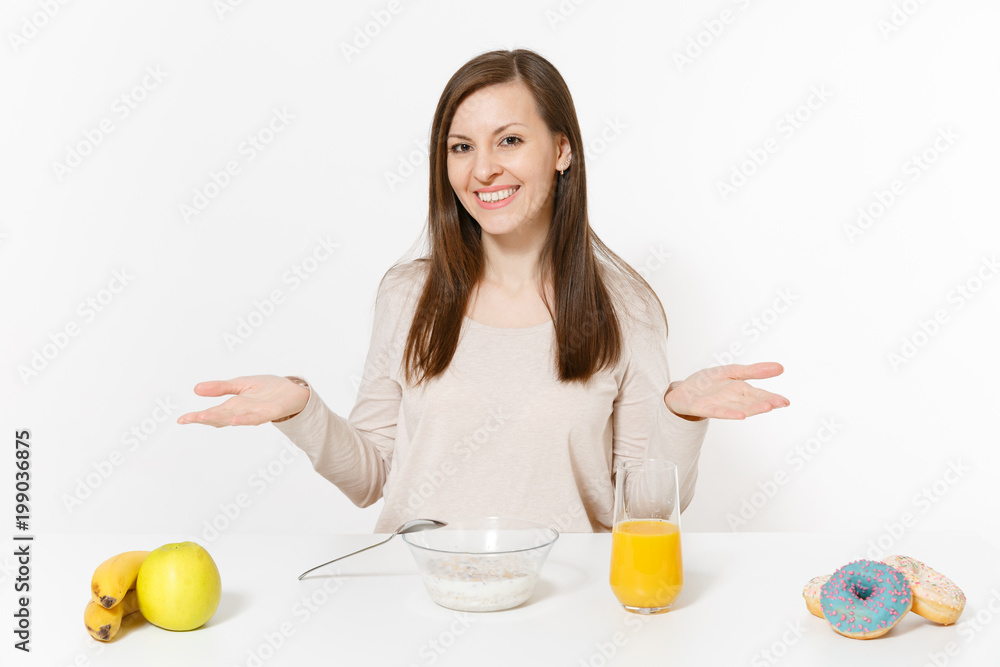 Young woman sitting at table breakfast with cereals and milk, orange juice in glass, donuts isolated on white background. Proper nutrition, delicious tasty food, healthy lifestyle. Area to copy space. Young woman sitting at table breakfast with cereals and milk, orange juice in glass, donuts isolated on white background. Proper nutrition, delicious tasty food, healthy lifestyle. Area to copy space.