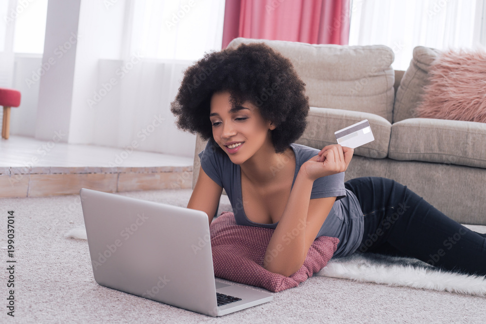 Let your online shopping be easy! A graceful beautiful young woman lying on the floor near her laptop and shopping with the credit card. Let your online shopping be easy! A graceful beautiful young woman lying on the floor near her laptop and shopping with the credit card.