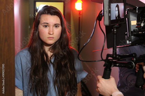 Young woman actress behind the scenes on a film or TV set, gear visible