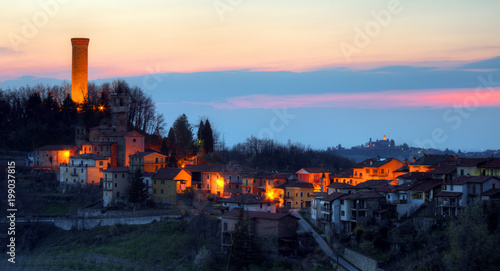 A small village in Italy. Night falls on Castellino Tanaro, in the Langhe, in Piedmont. Behind him is Rocca Ciglié, with its high illuminated tower.  photo