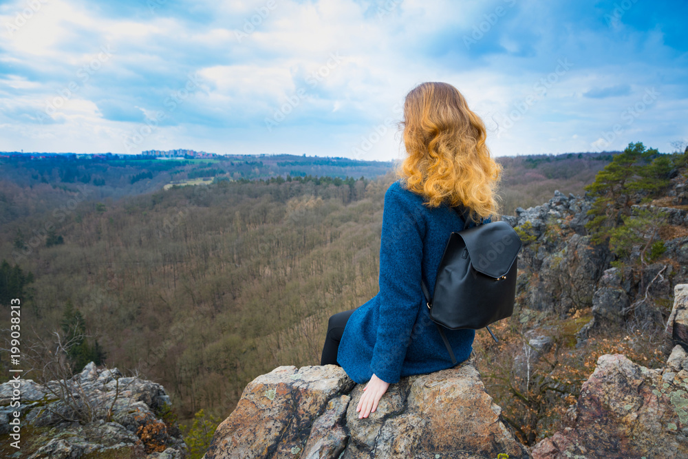 The girl sitting on the rock in mountain, relaxing in nature The girl sitting on the rock in mountain, relaxing in nature