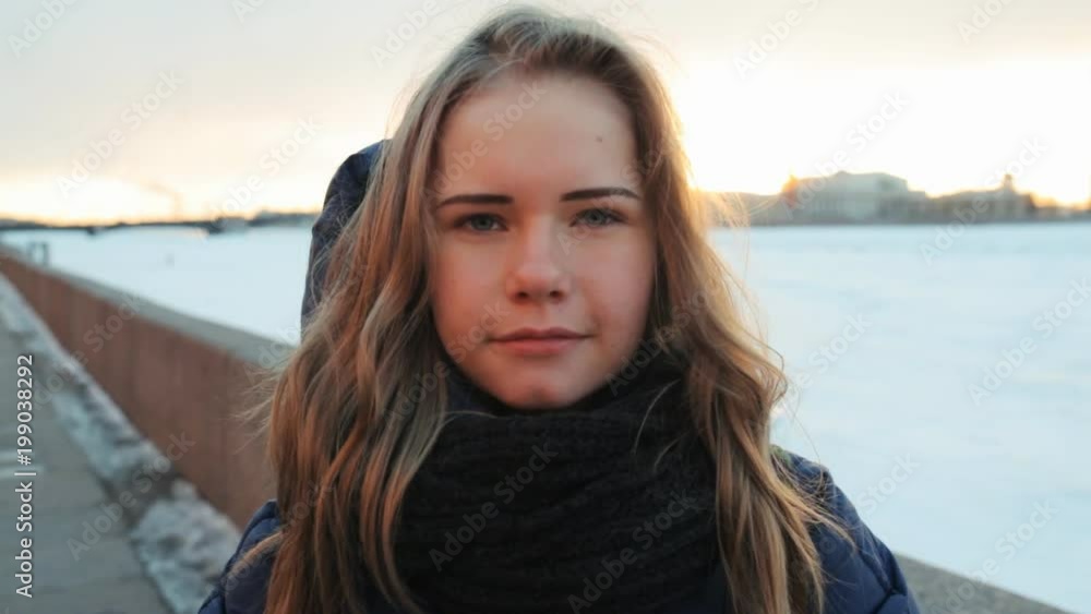 the girl smiles in the light of the setting sun and warms her hands with a steam from her mouth the girl smiles in the light of the setting sun and warms her hands with a steam from her mouth