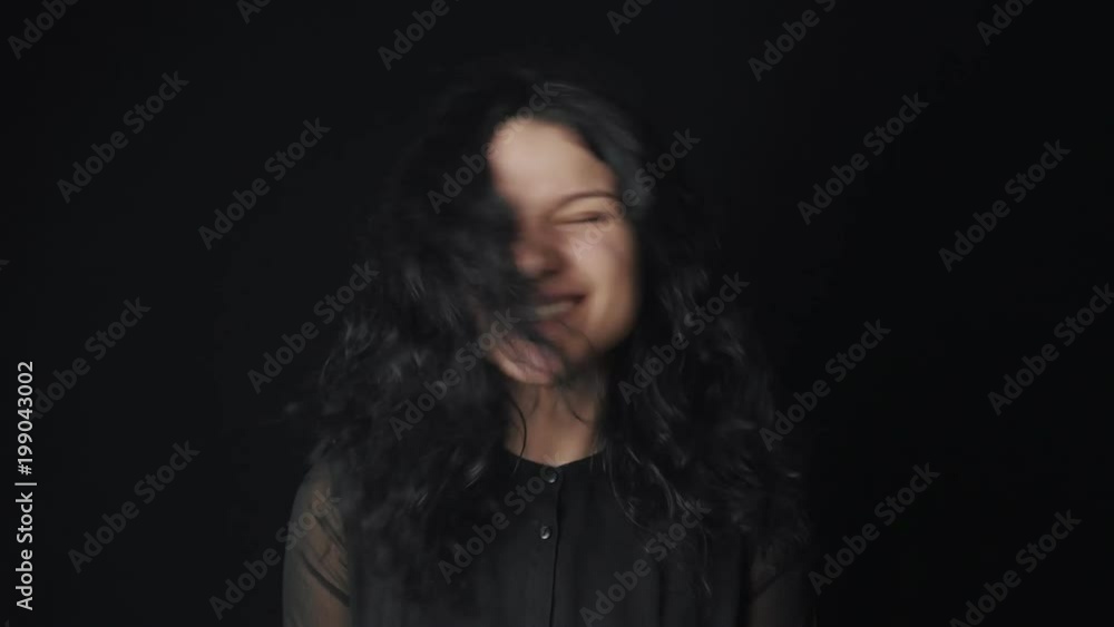 portrait of a cheerful young woman with curly hair who fools around and has fun on a black background portrait of a cheerful young woman with curly hair who fools around and has fun on a black background