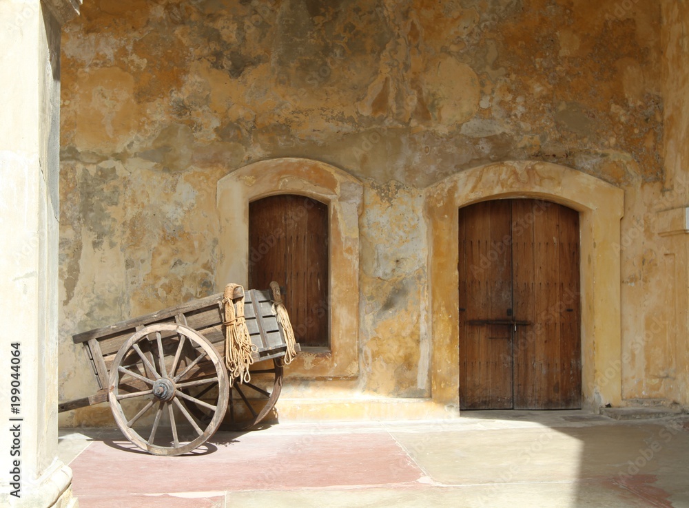 old wooden cart in front of two wooden doors against tan walls, Old San Juan, Puerto Rico, Caribbean