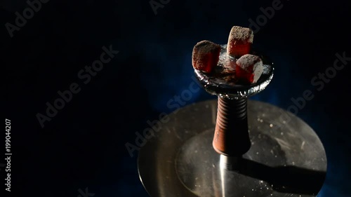 Modern clay phunnel Hookah bowl at the top of shisha with red hot coconut coals charcoal with a lot of smoke at black background isolated. Smoking at dark shisha lounge