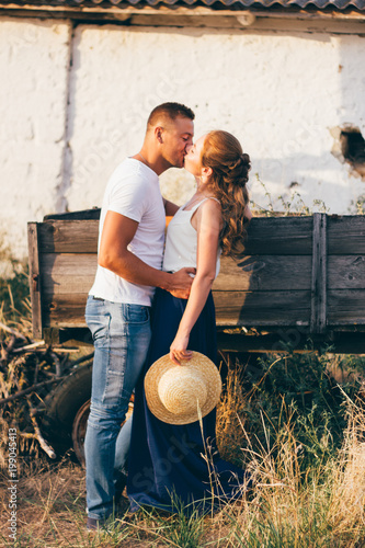 Beautiful guy and girl holding hands, kissing. Love story photo on outdoor in sunset light. Models. Couple in love. Pretty girl and brutal guy walking in outdoor. Shallow focus and some noise.