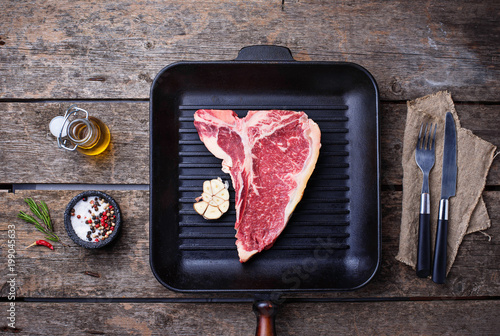 Raw T-bone steak on iron grill pan