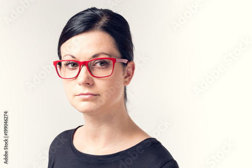 Portrait of a young woman with black hair and red glasses.