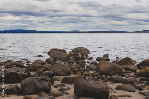 deserted beach in Hobart, Tasmania with rocks in the foreground