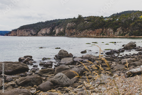 deserted beach in Hobart, Tasmania with rocks in the foreground