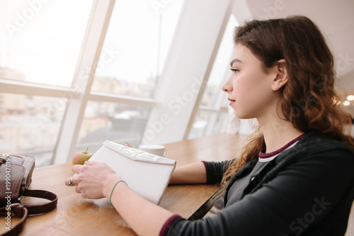 A girl sitting in a cafe  looking out the window