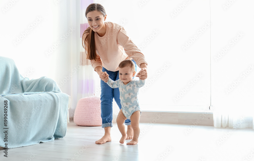 Baby taking first steps with mother's help at home - obrazy, fototapety, plakaty 