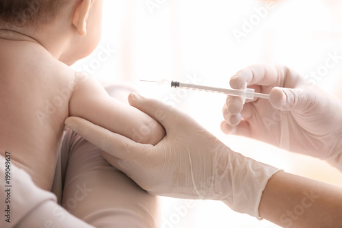 Doctor vaccinating baby in clinic  closeup
