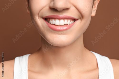 Young woman with beautiful smile on color background. Teeth whitening
