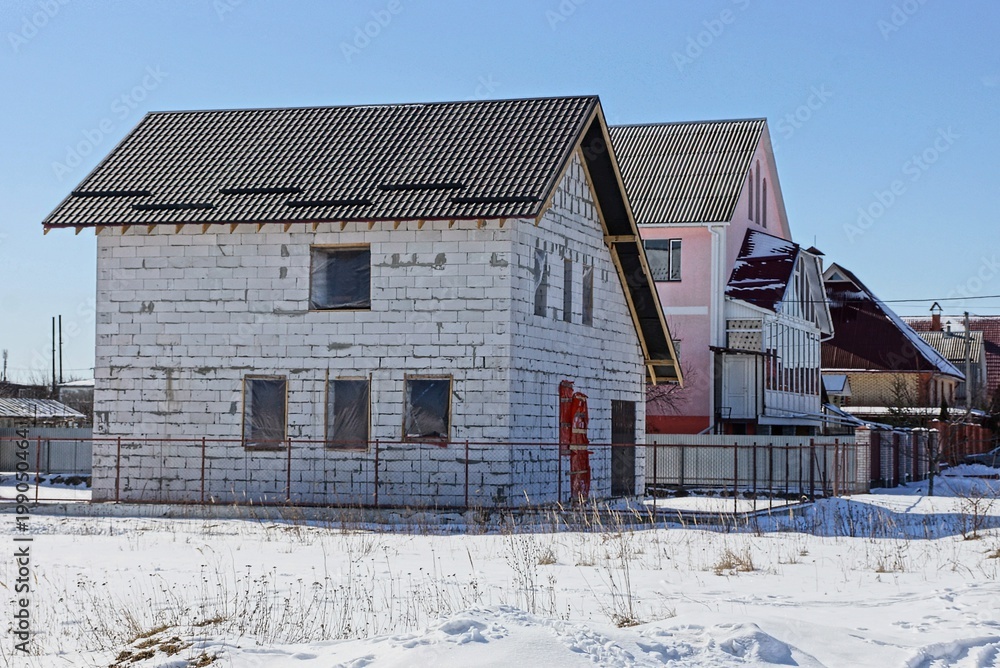 white unfinished brick house on a building site in the snow white unfinished brick house on a building site in the snow