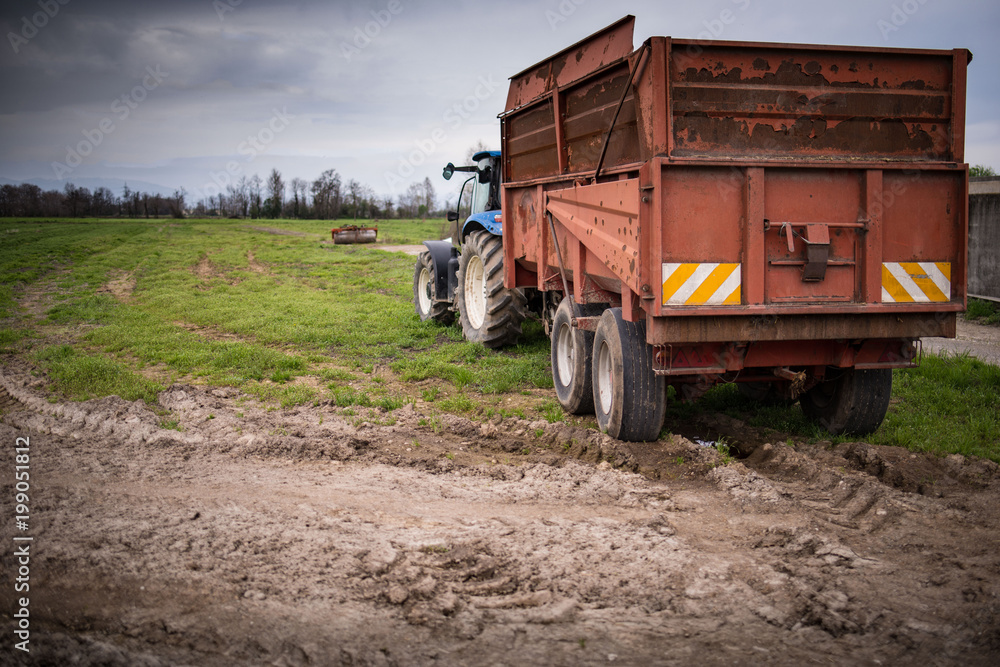 Obraz premium Trattore con carro agricolo al lavoro nei campi