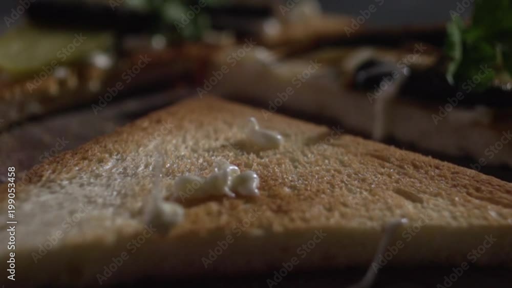 A jet of sauce pours on the surface of the toast. A jet of sauce pours on the surface of the toast.