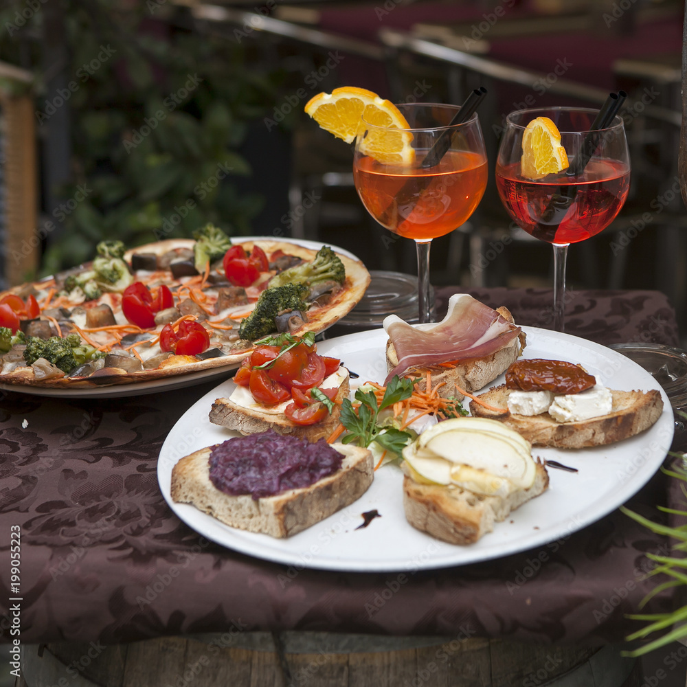 the Wine in glasses, plates with pizza and sandwiches with jamon and cheese on the table at the entrance to the restaurant the Wine in glasses, plates with pizza and sandwiches with jamon and cheese on the table at the entrance to the restaurant