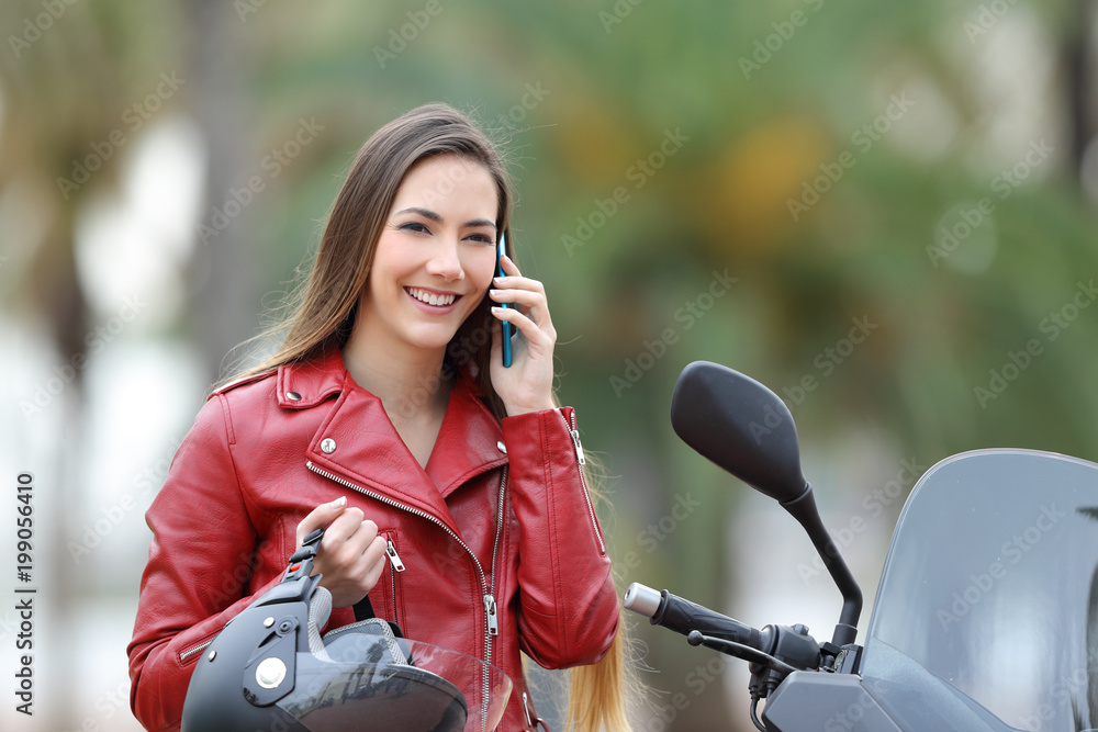 Fototapeta premium Biker calling on phone on a motorbike on the street