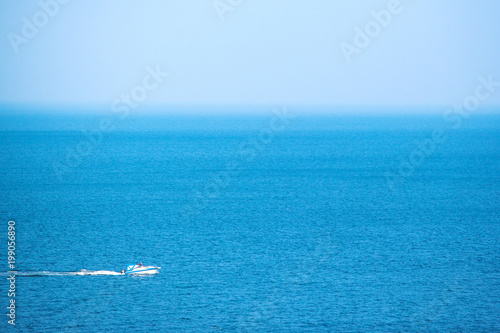 a small solitary white yacht sails in the middle of the blue sea © Sergey