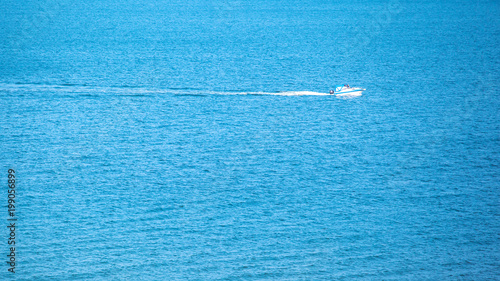 a small solitary white yacht sails in the middle of the blue sea