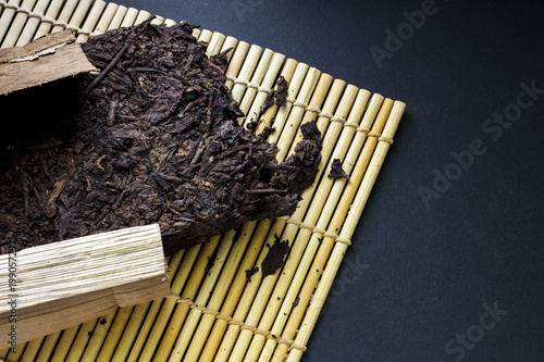 The composition of packed chinese puer tea on a bamboo mat. Black background. photo