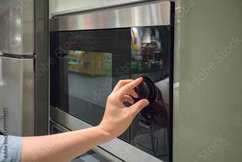 Woman's Hands adjusting timing button on microwave