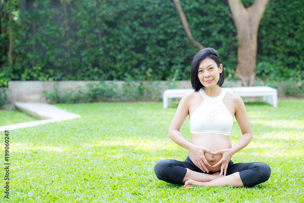 Happy pregnant beautiful young asian woman with gesture hand heart shape in the park, woman with hand touch belly with relax, mother love baby, family concept. Happy pregnant beautiful young asian woman with gesture hand heart shape in the park, woman with hand touch belly with relax, mother love baby, family concept.