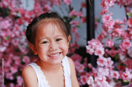 Smiling asian girl against blur background artificial sakura.